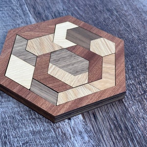 May include: A wooden hexagon puzzle with a geometric design. The puzzle is made of different shades of wood, including brown, light brown, and dark brown.