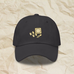 Może przedstawiać: Czarna czapka z daszkiem z haftowanym wzorem makaronu, w tym ravioli, makaronu w kształcie muszelki i widelca.