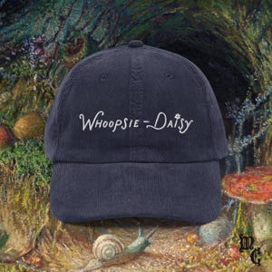 May include: Navy blue corduroy baseball cap with the embroidered text "Whoopsie-Daisy" in white script. The cap has a curved brim and a classic six-panel design. A stylish accessory for casual wear.
