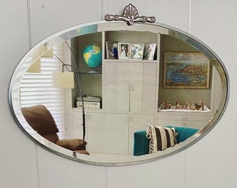 Art Deco beveled mirror with metal frame and decorative topper