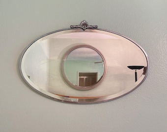 Art Deco beveled mirror with metal frame and decorative topper