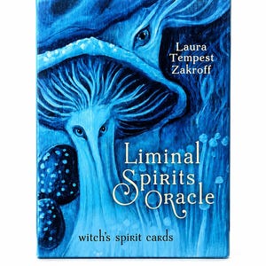 May include: A blue oracle card deck titled "Liminal Spirits Oracle" by Laura Tempest Zakroff. The cover art features a surreal illustration of blue mushrooms with eyes and the text "witch's spirit cards".