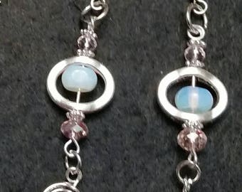 Moonstone  dangle earrings floating in a silver oval accented with pink crystals and a silver spiral swirl charm