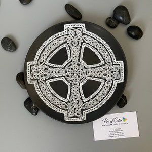 Könnte beinhalten: Ein schwarzer Keramikteller mit einem silbernen keltischen Knotendesign. Der Teller ist rund und hat einen erhöhten Rand. Das Design ist kompliziert und detailliert und ein wunderschönes Beispiel für keltische Kunst.