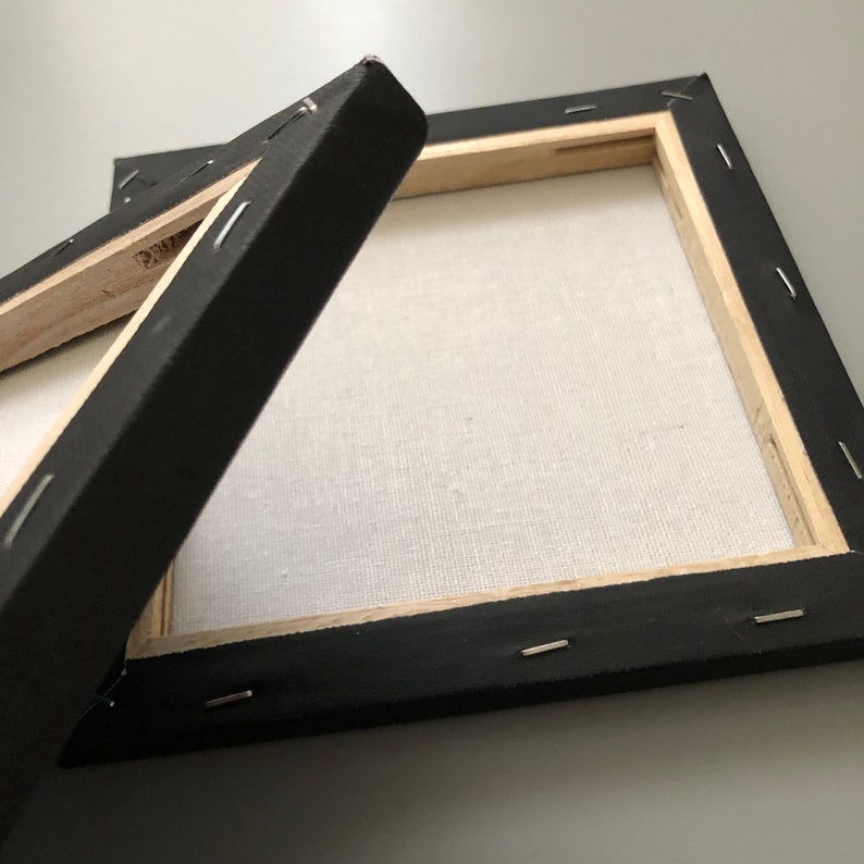 May include: Two black canvas frames with wooden stretcher bars and staples holding the canvas in place. The frames are empty and ready for painting.