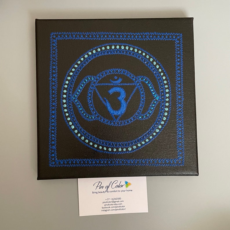 May include: A blue and teal mandala with the number 3 in the center, painted on a black canvas. The mandala is surrounded by a blue border.