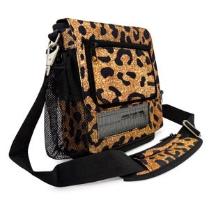 May include: A square shoulder bag featuring a gold and black leopard print. It has a black shoulder strap, a mesh side pocket, and a zipped front pocket. The bag is secured with a silver-coloured metal clasp.