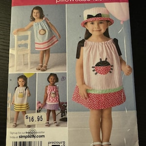 May include: Simplicity pillowcase fashions pattern featuring children's dresses. The pattern includes various dress designs with whimsical details, such as a ladybug and bee. The pattern is for sizes A 1/2, 1, 2, 3, and 4.