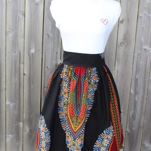 May include: A black knee-length skirt with a vibrant, colorful pattern. The skirt features a high waist and a bold, geometric design in red, yellow, blue, and green. The skirt is displayed on a white mannequin.