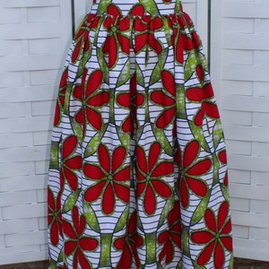 Peut inclure: Un t-shirt blanc avec un petit motif de c&oelig;ur marron et une longue jupe taille haute. La jupe pr&eacute;sente un motif floral vibrant avec des fleurs rouges, des feuilles vertes et des rayures blanches et noires.