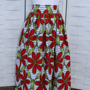 Peut inclure: Un t-shirt blanc avec un petit motif de double c&oelig;ur est associ&eacute; &agrave; une longue jupe fluide. La jupe pr&eacute;sente un motif floral vibrant en rouge et vert sur fond blanc avec des rayures noires. La jupe est fronc&eacute;e &agrave; la taille.