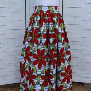 Peut inclure: Un t-shirt blanc avec un petit motif de c&oelig;ur, associ&eacute; &agrave; une longue jupe taille haute. La jupe pr&eacute;sente un motif floral vibrant en rouge, vert et blanc, cr&eacute;ant un look audacieux et accrocheur.