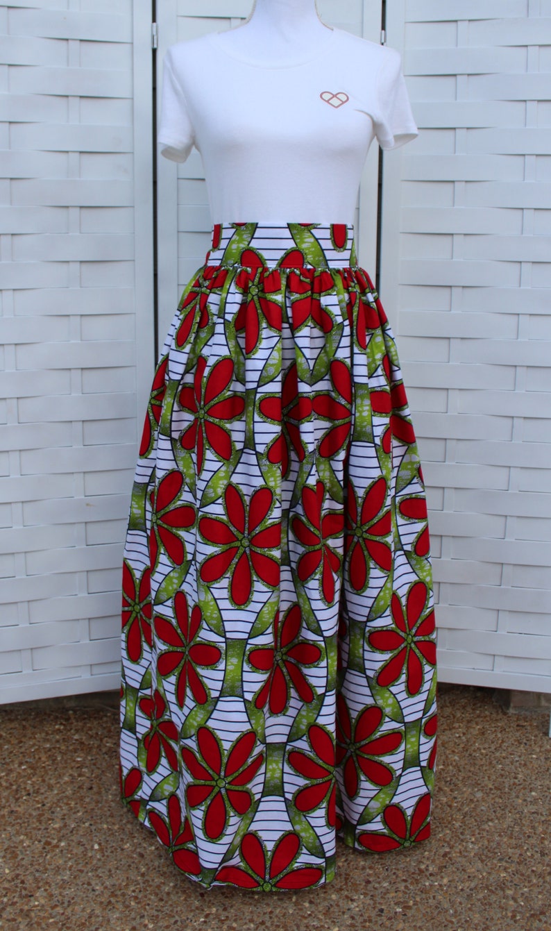 Peut inclure: Un t-shirt blanc avec un petit motif de c&oelig;ur, associ&eacute; &agrave; une longue jupe taille haute. La jupe pr&eacute;sente un motif floral vibrant en rouge, vert et blanc, cr&eacute;ant un look audacieux et accrocheur.