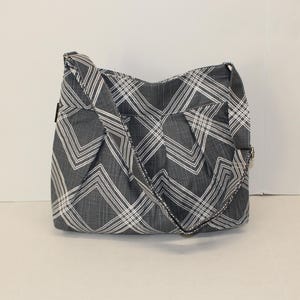 Medium-sized gray canvas crossbody bag with zip closure, adjustable strap and inside pockets