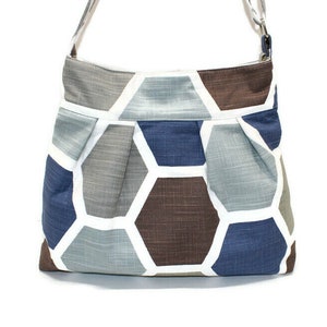 Bolso bandolera de lona con cierre de cremallera, bolsillos interiores y correa ajustable.