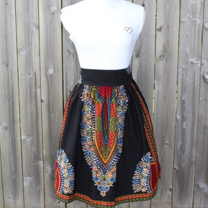 May include: A black skirt with a vibrant, colorful pattern. The skirt features a wide black waistband and a knee-length hem. The design includes red, yellow, blue, and green accents, creating a bold and eye-catching look.