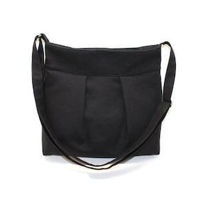 Black canvas medium-size zipper crossbody bag with adjustable strap and inside pockets