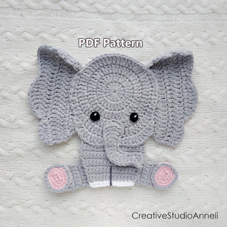 May include: A crocheted gray elephant with large ears, black eyes, and pink foot pads. The text "PDF Pattern" is above the elephant. The elephant is lying on a white surface. The text "CreativeStudioAnneli" is below the elephant.
