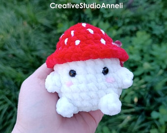 Puede incluir: Un peluche de hongo blanco con un gorro rojo salpicado de puntos blancos. El hongo tiene ojos negros y mejillas rosadas. El texto "CreativeStudioAnneli" está en la esquina superior izquierda.