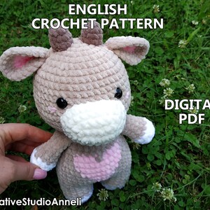 May include: Crochet pattern for a cute brown and white cow amigurumi toy. The pattern is available as a digital PDF download. The image shows the finished toy.