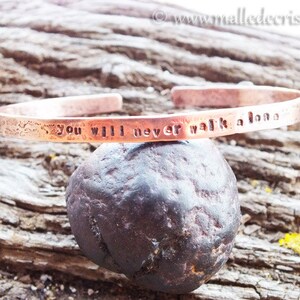 Peut inclure: Un bracelet en cuivre avec l'inscription "You will never walk alone".