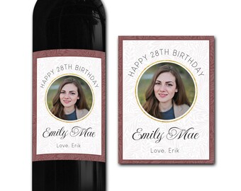 Puede incluir: Una etiqueta de botella de vino con un patrón floral rosa y blanco. La etiqueta presenta una foto de una mujer con el texto "Happy 28th Birthday Emily Mae Love. Erik".