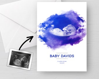 Puede incluir: Una tarjeta blanca con un fondo de acuarela azul y morado presenta una imagen de ultrasonido de un feto. El texto "BABY DAVIDS" está debajo de la imagen, con "12 WEEK SCAN" y la fecha "13.04.19" debajo. También hay un sobre y una pequeña foto de ultrasonido.