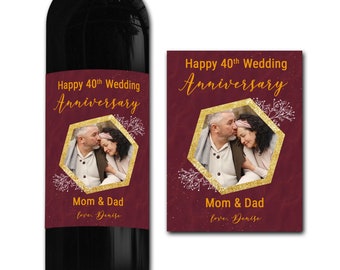 Puede incluir: Una etiqueta de botella de vino burdeos con detalles de purpurina dorada. La etiqueta presenta una foto de una pareja, una forma hexagonal y el texto "Happy 40th Wedding Anniversary Mom & Dad love. Denise".