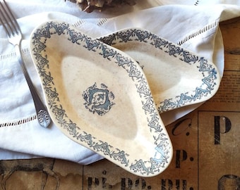 May include: Two white oval serving dishes with blue and green floral designs. The dishes are on a white tablecloth with a floral pattern.