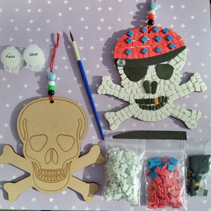 May include: A craft kit for making a pirate skull mosaic. The kit includes a wooden skull and crossbones template, mosaic tiles in white, red and blue, glue, paint and a paintbrush.