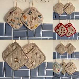 May include: Set of 10 oven mitts with various patterns. The mitts are beige with quilted fabric and feature designs of butterflies, ducks, and red polka dots.