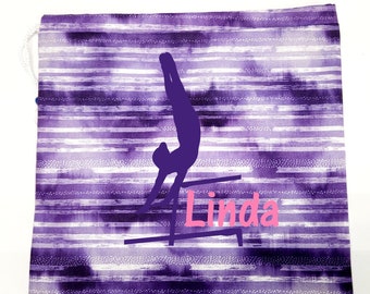 May include: Purple and white striped drawstring bag with a silhouette of a gymnast on uneven bars and the name "Linda" in pink lettering.