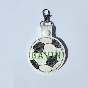 May include: White leather keychain with a black and white soccer ball design and the name "GAVIN" embroidered in green.
