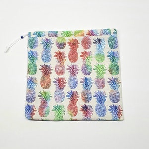 May include: A white reusable shopping bag with a drawstring closure. The bag is decorated with a repeating pattern of colorful pineapples.