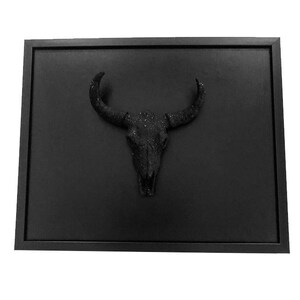 May include: A black framed wall art piece featuring a black, glittery bull skull.