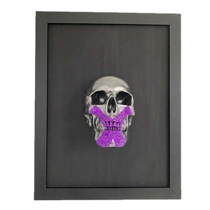 May include: A silver skull with a purple X over its mouth, framed in black.