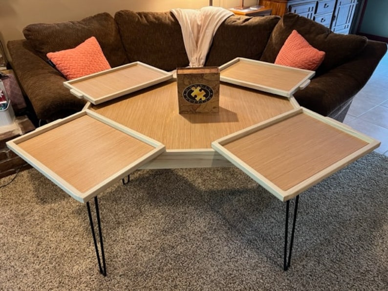 May include: A hexagonal coffee table with four removable trays. The table has a light wood finish and black hairpin legs. A wooden puzzle box sits in the centre of the table.