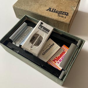 May include: Vintage Allegro Mod. L shaving kit in a green box with a brown lid. The kit includes a Persona Super Stainless razor, Gillette Silver Stainless blades, and Minora 5 Blades. The box is open, revealing the contents.