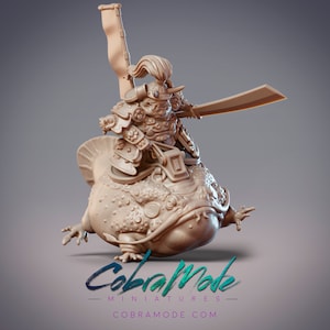 May include: A 3D printed miniature of a frog wearing samurai armor and holding a sword. The frog is standing on its hind legs and has a flag on its back. The miniature is painted in a light brown color.