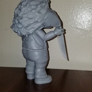 K&ouml;nnte beinhalten: Eine graue 3D-gedruckte Figur eines Charakters mit einem Messer. Der Charakter hat einen pelzigen Kopf und tr&auml;gt eine Hose und eine Jacke.