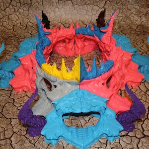 May include: A set of 8 colorful 3D printed dragon skull pieces. The skulls are in various shades of blue, pink, purple, gray, and yellow. The skulls are arranged in a circle, with the top of the circle open.