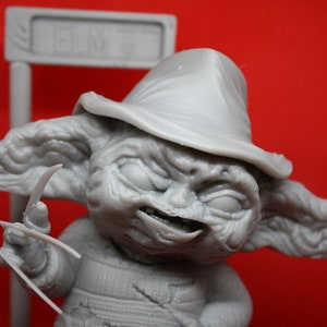 May include: A gray, detailed figurine of a character with a hat and sharp claws. The character has a menacing expression and appears to be a fictional creature.