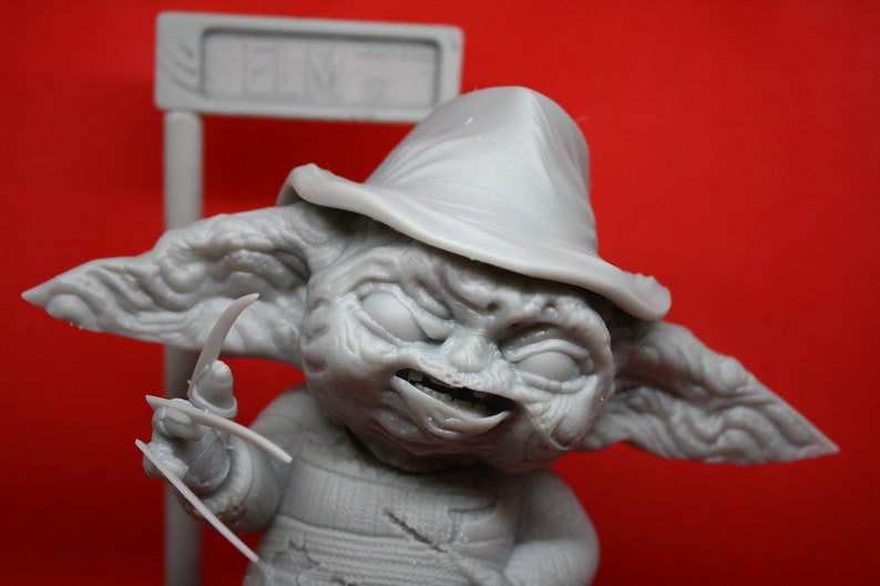 May include: A gray, detailed figurine of a character with a hat and sharp claws. The character has a menacing expression and appears to be a fictional creature.