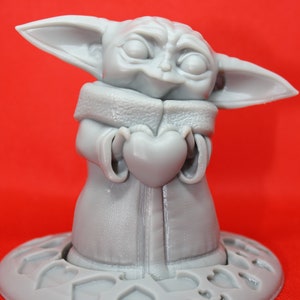 K&ouml;nnte beinhalten: Eine graue 3D-gedruckte Figur eines Charakters aus dem Star Wars-Franchise, die ein Herz in ihren H&auml;nden h&auml;lt. Die Figur steht auf einem herzf&ouml;rmigen Sockel.