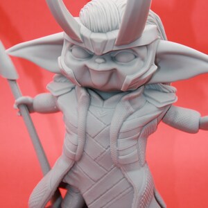 May include: A grey 3D printed figurine of a character with horns, a pointed hat, and a long robe. The character is holding a spear in its right hand and has a mischievous expression on its face.