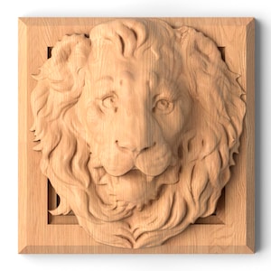 Può includere: Un'intaglio in legno della testa di un leone, centrata in una cornice quadrata. Il volto del leone è dettagliato con peli e lineamenti. Il legno è di un colore marrone chiaro naturale.