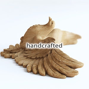 May include: A handcrafted wooden sculpture of a bird in flight, with outstretched wings. The sculpture is made of light-colored wood and features detailed carving of feathers and body. The word "handcrafted" is displayed on the sculpture.