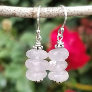 May include: Silver dangle earrings with three stacked pale pink rose quartz beads.