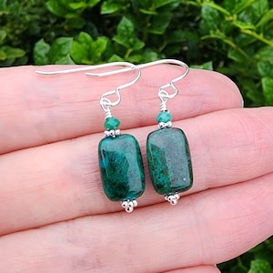 May include: A pair of silver earrings with green malachite stones and green crystal accents.