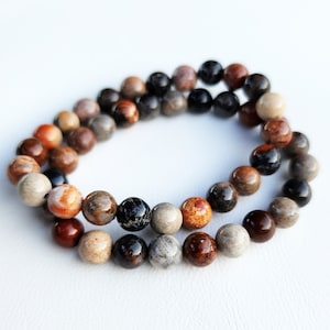 Puede incluir: Un brazalete de cuentas multicolores con cuentas marrones, negras y blancas. El brazalete est&aacute; hecho de piedra natural y tiene un aspecto r&uacute;stico.
